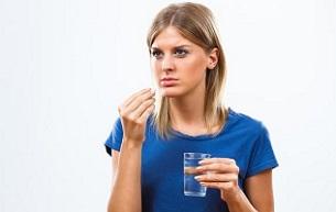 portrait-of-a-woman-holding-a-glass-of-water-and-pill.jpg