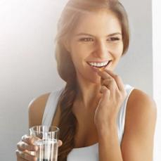 smiling-woman-holding-a-glass-of-water-and-supplement.jpg