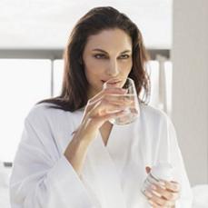 a-woman-takes-medication-with-water-in-a-bathroom.jpg