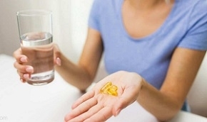 Woman Holding Glass of Water and Pills