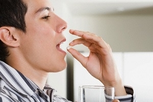 Man Holding Glass of Water and Pill