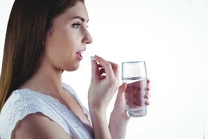Woman Holding Pill and Glass of Water